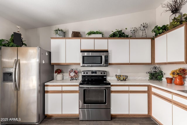 kitchen with light countertops, appliances with stainless steel finishes, white cabinetry, and wood finished floors
