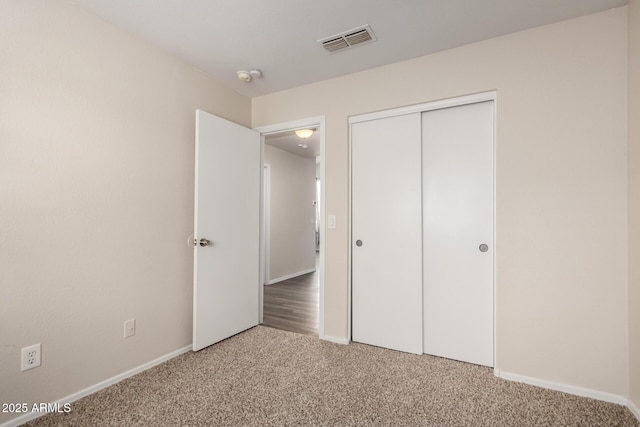 unfurnished bedroom featuring visible vents, carpet, baseboards, and a closet