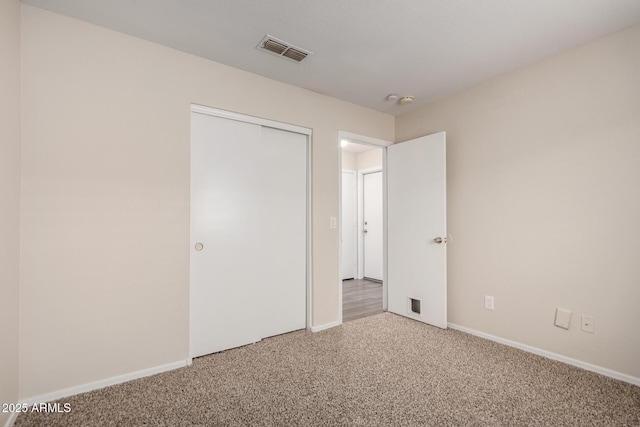 unfurnished bedroom featuring carpet floors, baseboards, a closet, and visible vents
