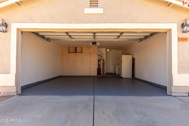 garage featuring freestanding refrigerator, water heater, separate washer and dryer, a garage door opener, and concrete driveway