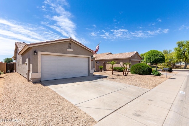 ranch-style home featuring fence, stucco siding, concrete driveway, an attached garage, and a tile roof