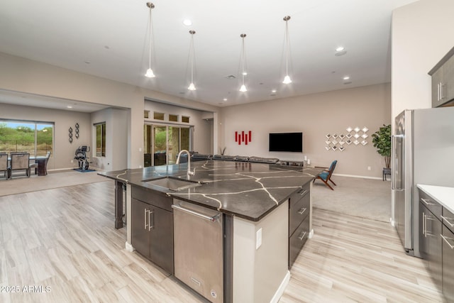 kitchen featuring appliances with stainless steel finishes, a large island, decorative light fixtures, and sink