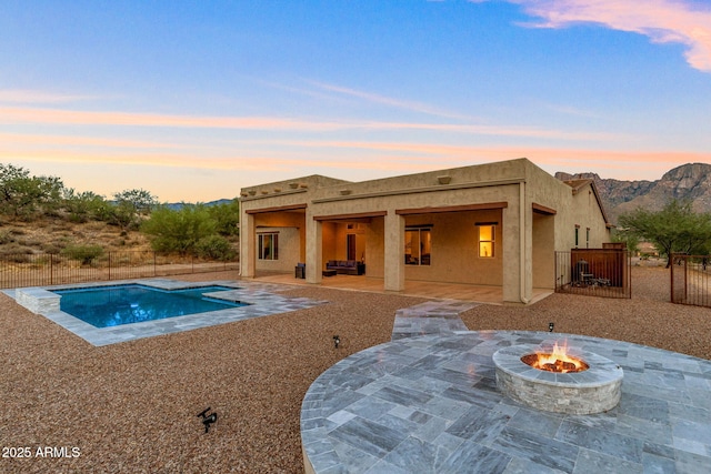 pool at dusk featuring a mountain view, a patio, and an outdoor fire pit