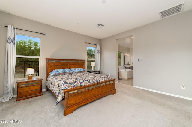 bedroom with ensuite bath and light carpet