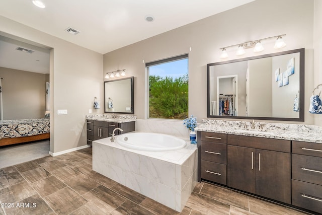 bathroom featuring tiled tub and vanity