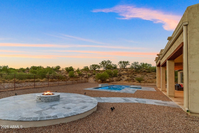 pool at dusk with a patio area and an outdoor fire pit