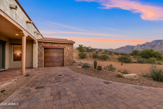 patio terrace at dusk with a garage and a mountain view