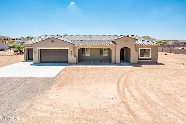 mediterranean / spanish house featuring an attached garage, fence, a tiled roof, stucco siding, and driveway