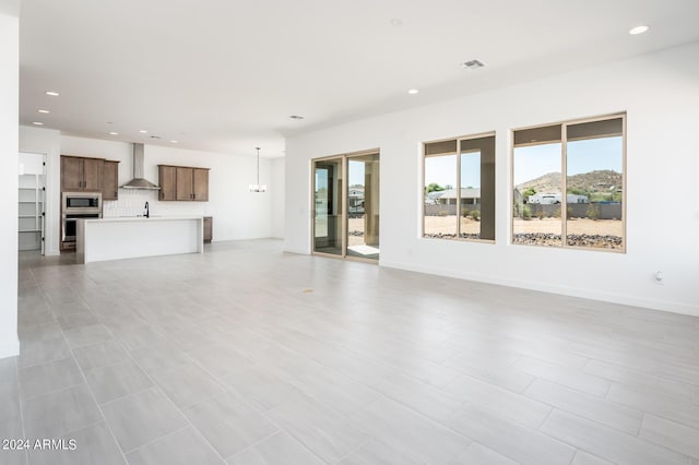 unfurnished living room featuring visible vents, a notable chandelier, a sink, recessed lighting, and baseboards