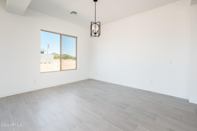 spare room featuring visible vents, baseboards, and an inviting chandelier