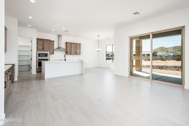 kitchen featuring visible vents, open floor plan, light countertops, stainless steel appliances, and wall chimney exhaust hood