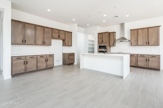 kitchen featuring stainless steel microwave, light countertops, wall chimney exhaust hood, and a sink