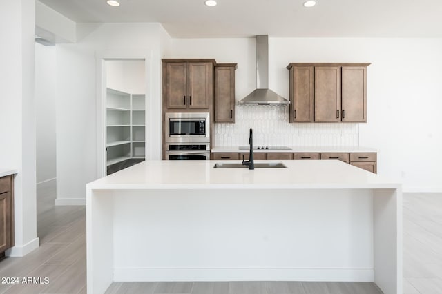 kitchen with decorative backsplash, light countertops, wall chimney range hood, and appliances with stainless steel finishes