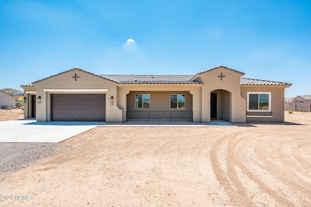 mediterranean / spanish house featuring stucco siding, an attached garage, driveway, and a tile roof