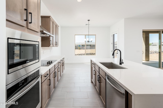 kitchen with extractor fan, an island with sink, light countertops, stainless steel appliances, and a sink