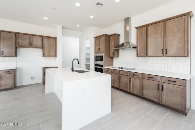 kitchen featuring visible vents, stainless steel appliances, a sink, light countertops, and wall chimney exhaust hood