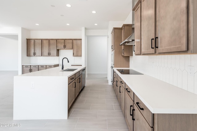 kitchen with an island with sink, a sink, extractor fan, appliances with stainless steel finishes, and tasteful backsplash