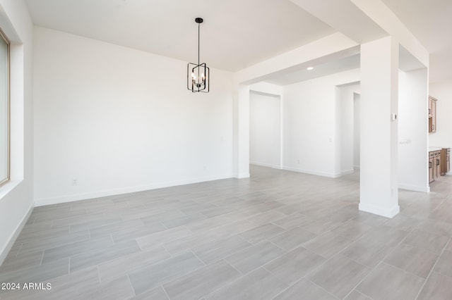 unfurnished room featuring baseboards and a chandelier