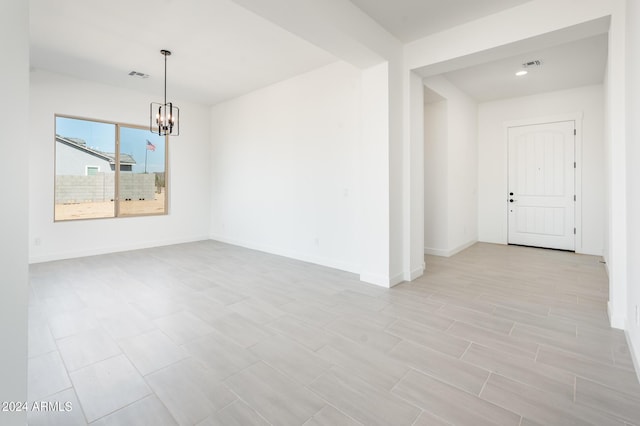 spare room with a notable chandelier, baseboards, and visible vents