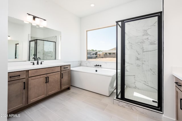 full bath featuring vanity, a freestanding tub, and a marble finish shower