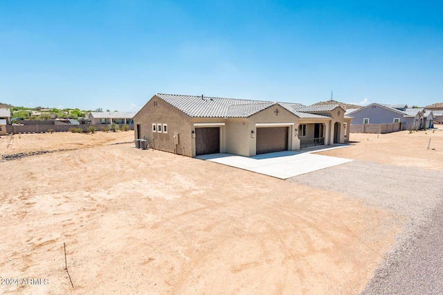 view of front of property with stucco siding, central AC, dirt driveway, fence, and a garage