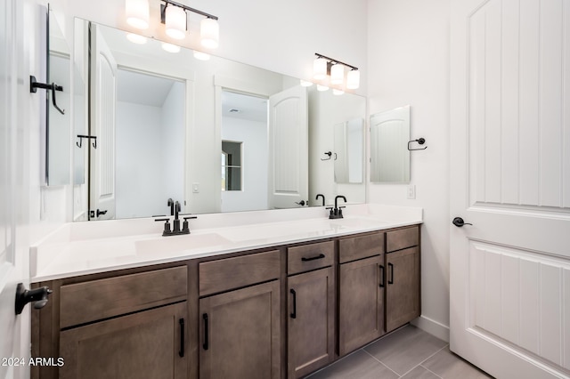 full bath with a sink, double vanity, and tile patterned flooring