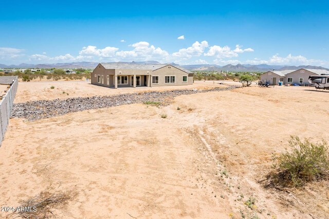 back of property with stucco siding, a mountain view, and fence