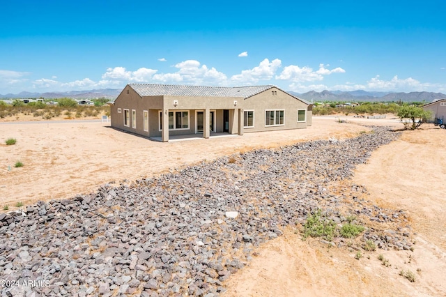 back of house with stucco siding, a patio, and a mountain view