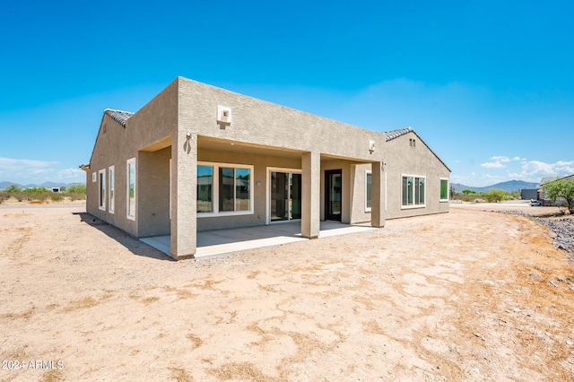 back of house featuring a patio area, stucco siding, and a mountain view