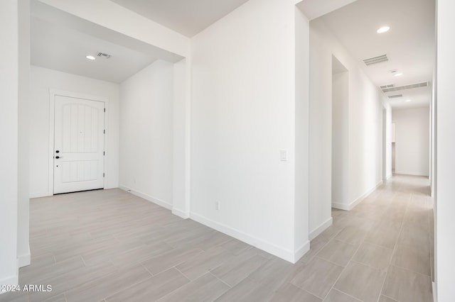 hallway with recessed lighting, visible vents, baseboards, and light wood finished floors