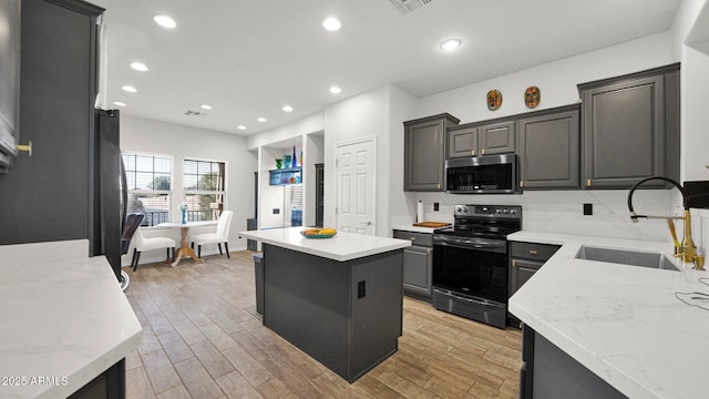 kitchen with black / electric stove, light wood-style flooring, a sink, a center island, and stainless steel microwave