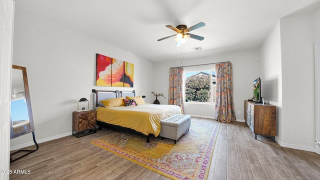 bedroom featuring visible vents, ceiling fan, baseboards, and wood finished floors