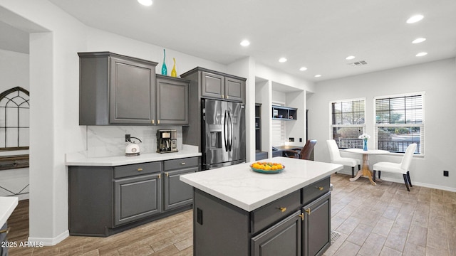 kitchen featuring gray cabinets, visible vents, decorative backsplash, light wood-type flooring, and stainless steel fridge with ice dispenser