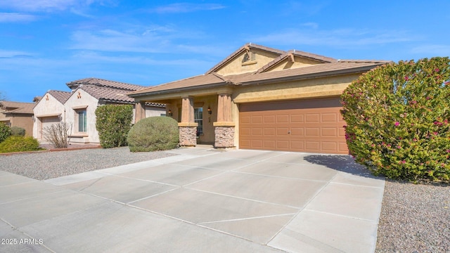 view of front facade with stucco siding, an attached garage, stone siding, driveway, and a tiled roof