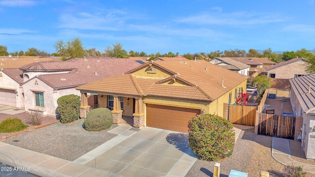 view of front facade featuring a tile roof, stucco siding, fence, a garage, and driveway