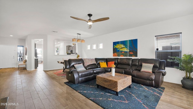 living area featuring a ceiling fan, a healthy amount of sunlight, and wood finished floors