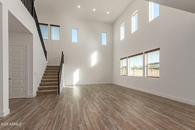 unfurnished living room featuring a towering ceiling and hardwood / wood-style floors