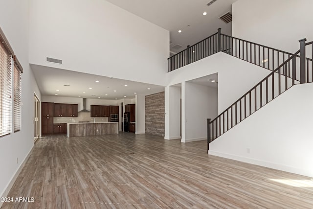 unfurnished living room with wood-type flooring and a high ceiling