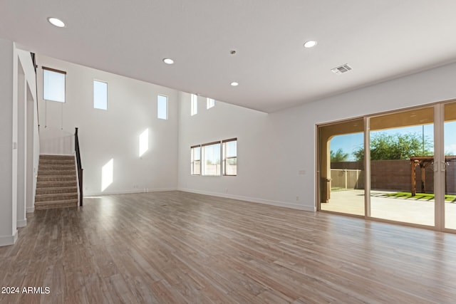 unfurnished living room with a high ceiling and light hardwood / wood-style flooring