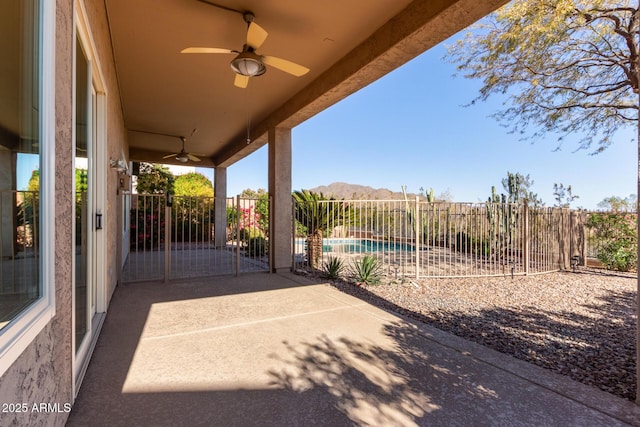 view of patio featuring a fenced backyard, a fenced in pool, a mountain view, and a ceiling fan