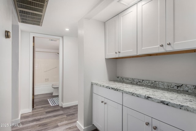 7402 E Carefree Dr Unit 319, Carefree, AZ 85377 - bar with light stone counters, light hardwood / wood-style flooring, and white cabinets