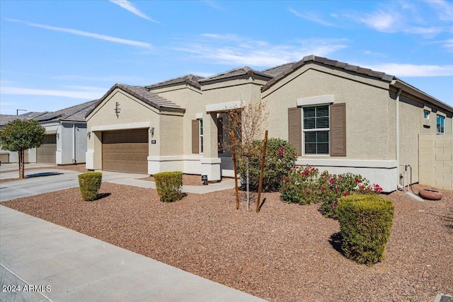 view of front of property with driveway, stucco siding, a tiled roof, and an attached garage