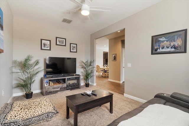 carpeted living room with visible vents, baseboards, and ceiling fan