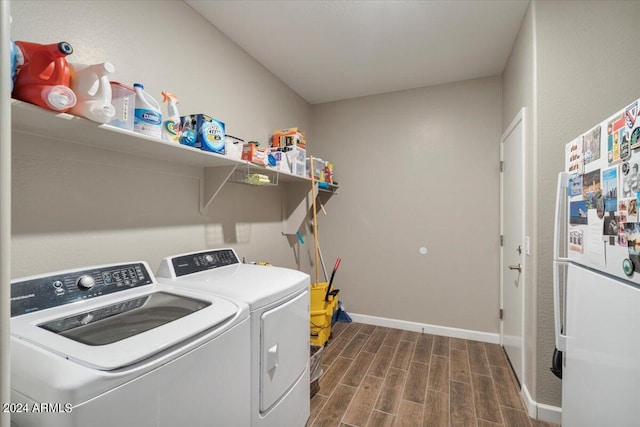 laundry area with laundry area, separate washer and dryer, baseboards, and wood finish floors