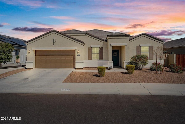 mediterranean / spanish house featuring concrete driveway, stucco siding, an attached garage, and a tile roof