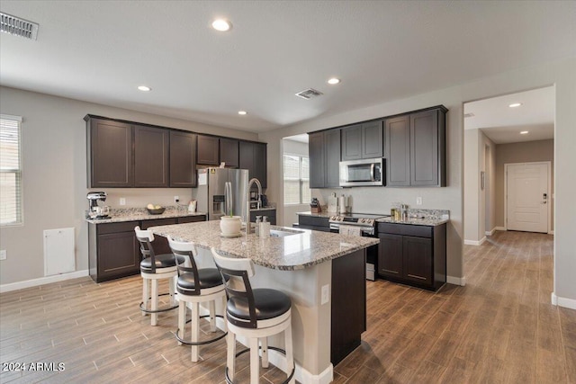 kitchen with a center island with sink, stainless steel appliances, plenty of natural light, and a kitchen breakfast bar