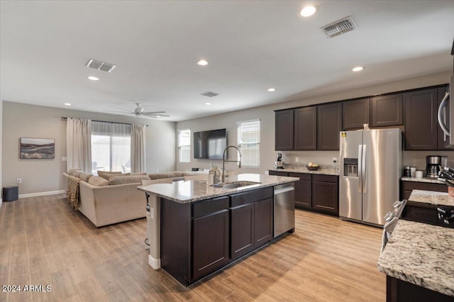 kitchen with sink, dark brown cabinets, a kitchen island with sink, light hardwood / wood-style flooring, and stainless steel appliances