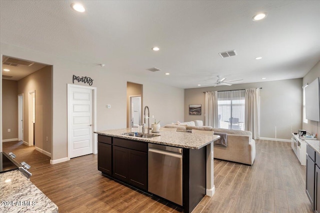 kitchen with light wood-type flooring, light stone counters, sink, a center island with sink, and dishwasher