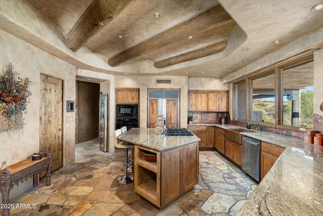 kitchen with sink, beam ceiling, a center island, black appliances, and light stone countertops