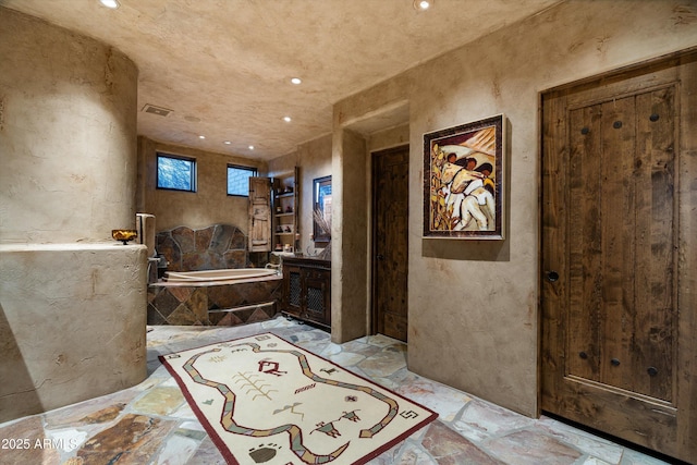 bathroom with vanity and tiled bath